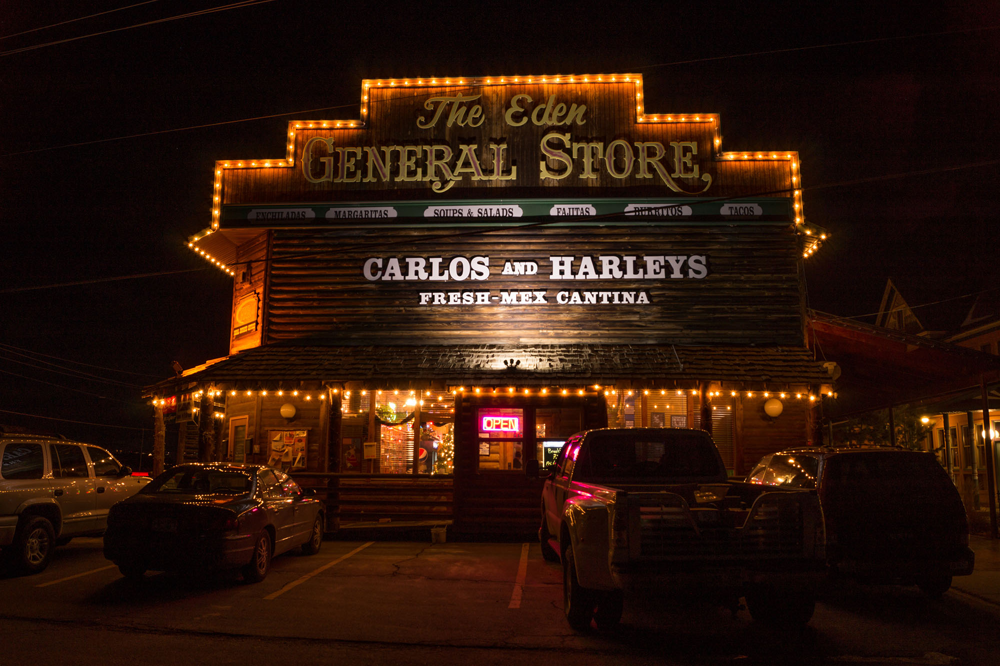 Carlos and Harleys restaurant at night with a glowing open sign.